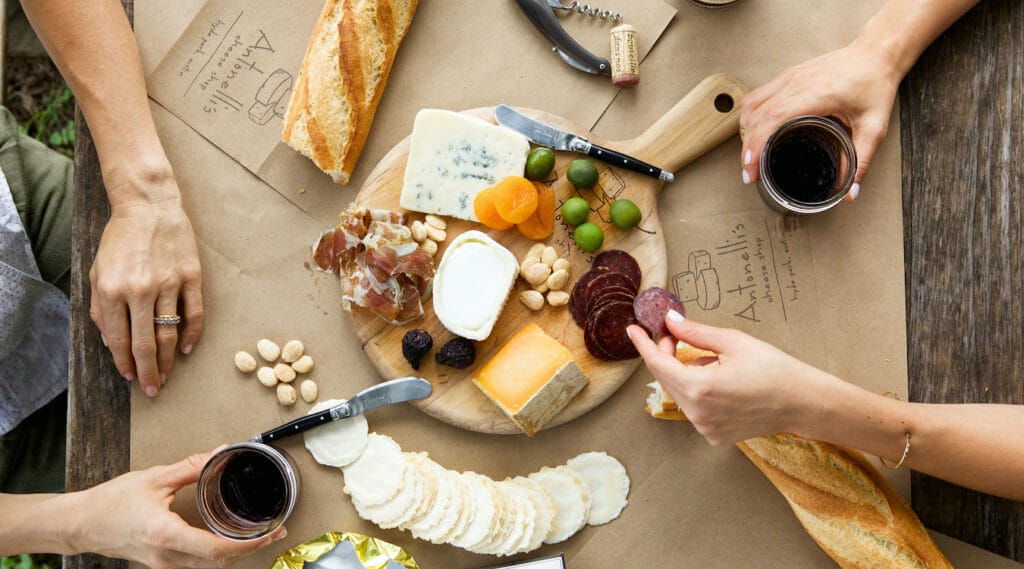 A charcuterie board by Antonelli's with various hands reaching in